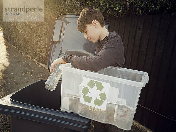 Boy putting separated recycling waste in waste bin