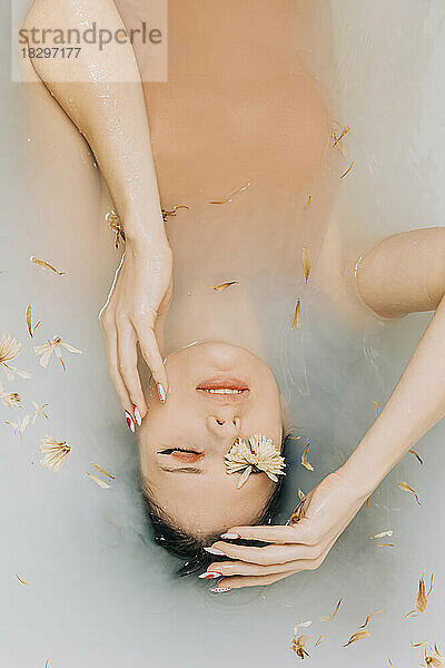 Girl taking bath with flowers in bathtub