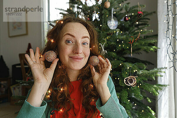 Lächelnde Frau mit Ohrringen vor dem Weihnachtsbaum