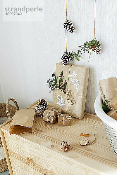 Christmas gift boxes with decorated pine cones kept on cabinet