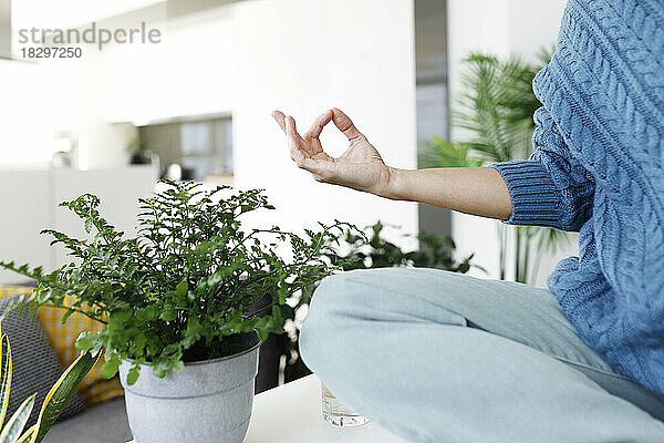 Woman sitting on table and meditating at home