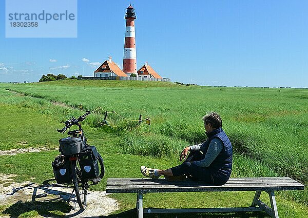 Frau sitzt auf einer Bank am Leuchtturm Westerheversand  Schleswig-Holstein  Deutschland  Europa