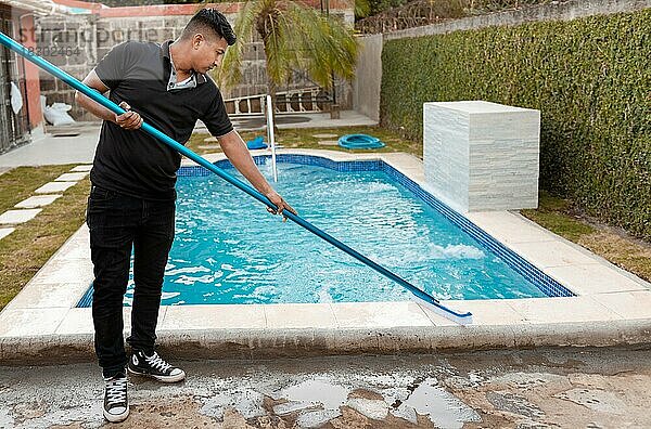 Schwimmbadreinigung mit Bürste. Wartungsperson  die ein Schwimmbad mit einer Bürste reinigt  Arbeiter  der ein Schwimmbad mit einer speziellen Bürste reinigt