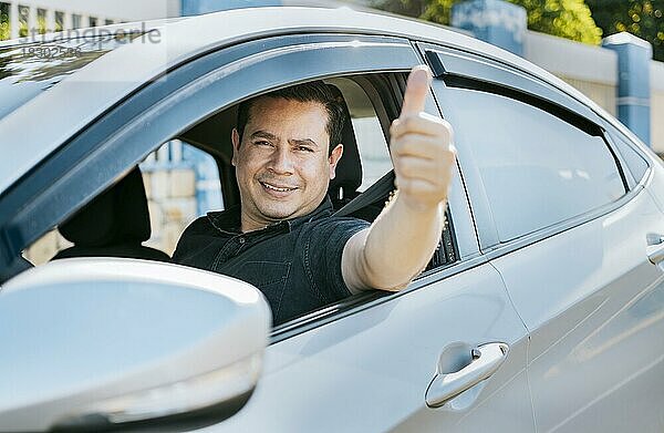 Mann in seinem Auto gibt Daumen hoch  Happy Driver gibt einen Daumen hoch. Zufriedener Fahrer Mann zeigt Daumen hoch. Konzept der zufriedenen Autobesitzer