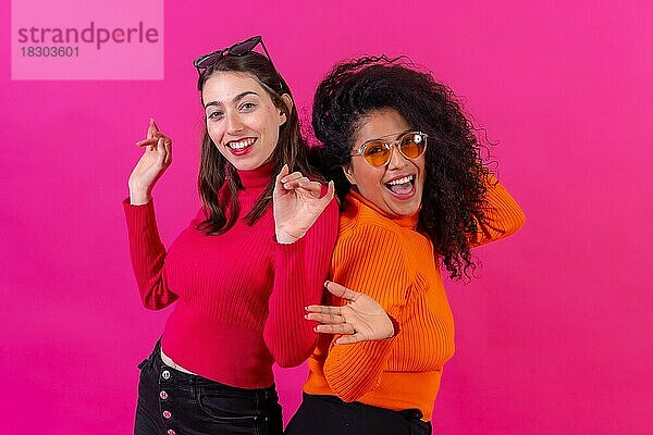 Freundinnen mit Sonnenbrillen  die Spaß haben und auf einem rosa Hintergrund tanzen  Studioaufnahme  Lifestyle
