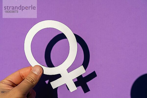 Eine Frau  die das weibliche Symbol auf einem lila Hintergrund hält  marschiert für Frauenrechte und Gleichberechtigung