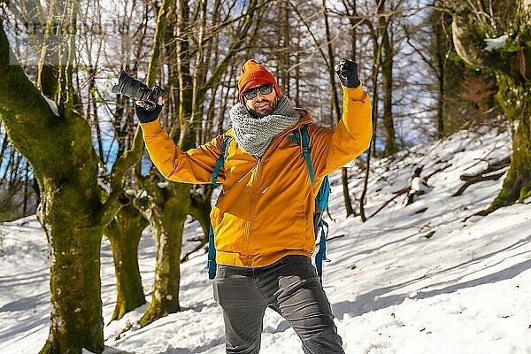 Porträt eines Fotografen  der mit einem Rucksack wandert und Fotos in einem Buchenwald mit Schnee  Spaß und Winterhobbys macht