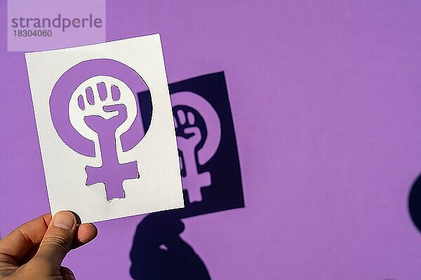 Eine Frau hält das Symbol des Kampfes für den Feminismus auf einem lila Hintergrund  geballte Faust einer Frau auf dem Marsch Proteste für Frauenrechte und Gleichheit