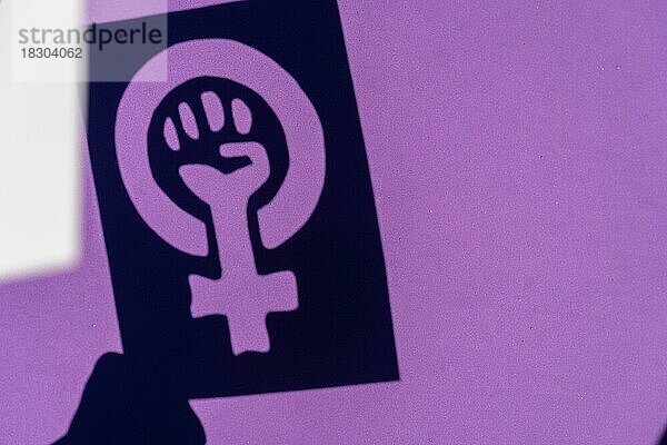 Schatten des Symbols des Kampfes für den Feminismus auf einem lila Hintergrund  geballte Faust einer Frau im Marsch Proteste für die Rechte der Frauen und für die Gleichstellung
