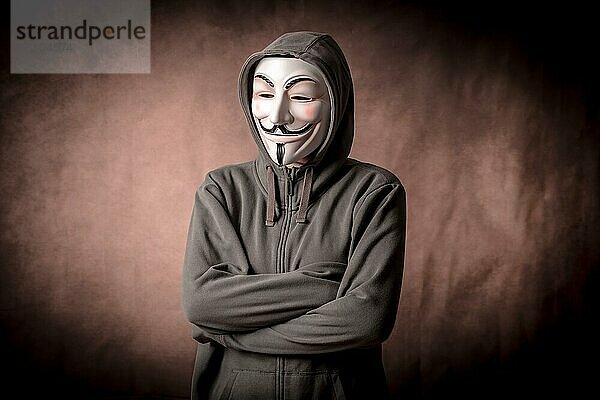 Mann mit anonymer Maske und Sweatshirt  Blick nach unten  Studioaufnahme