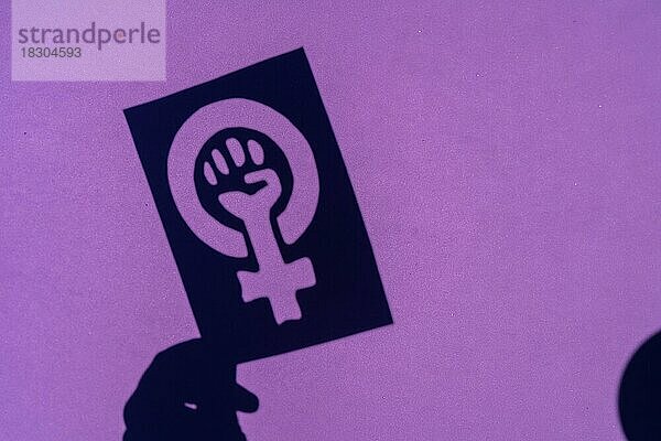 Schatten des Symbols des Kampfes für den Feminismus auf einem lila Hintergrund  geballte Faust einer Frau im Marsch Proteste für die Rechte der Frauen