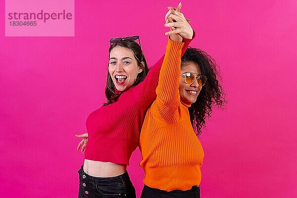 Freundinnen mit Sonnenbrillen  die Spaß haben und auf einem rosa Hintergrund tanzen  Studioaufnahme  Lifestyle