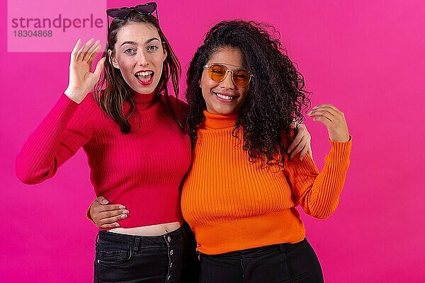 Weibliche Freunde mit Sonnenbrille  die Spaß haben und lächelnd auf einem rosa Hintergrund  Studioaufnahme  Lifestyle