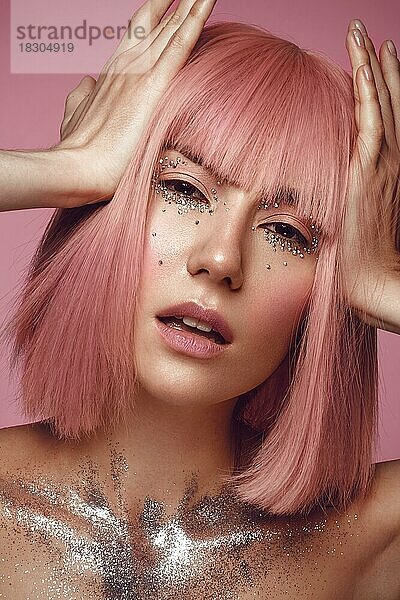 Schöne Frau in einer rosa Perücke und kreativem Make-up mit Strasssteinen. Schönes Gesicht. Foto im Studio aufgenommen