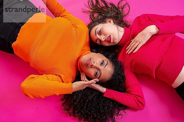 Zwei multiethnische Frauen in trendiger Pose auf rosa Hintergrund  Lifestyle