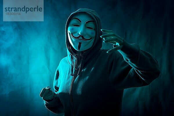 Hacker mit anonymen Maske mit einem Symbol des Kampfes  mit einem Hintergrund von Rauch und blau geführt