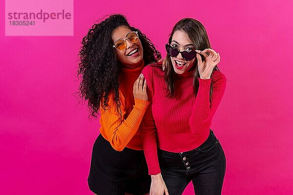 Weibliche Freunde mit Sonnenbrille haben Spaß rosa Hintergrund  Studioaufnahme