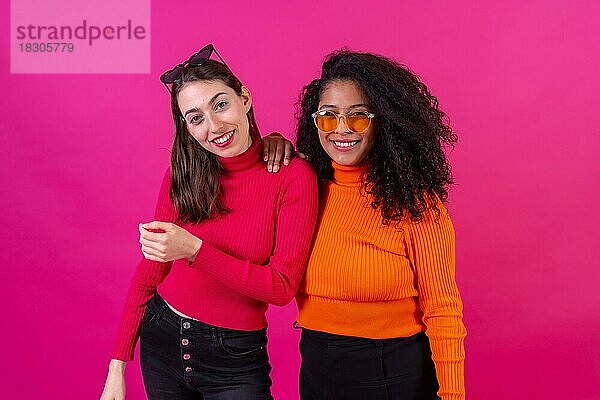 Portrait Freundinnen mit Sonnenbrille  die sich auf einem rosa Hintergrund amüsieren  Studioaufnahme  Lifestyle