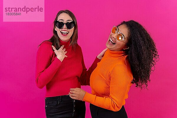 Weibliche Freunde mit Sonnenbrille haben Spaß rosa Hintergrund  Studioaufnahme
