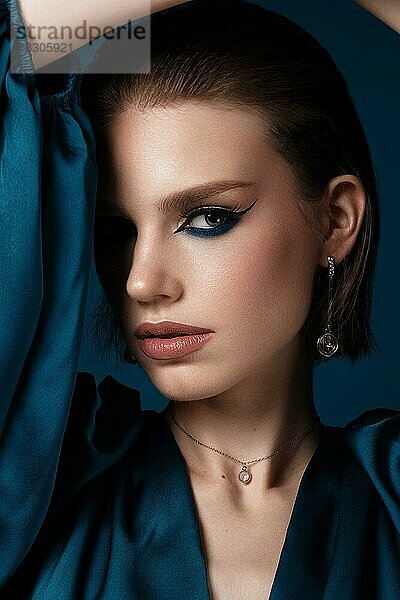 Schöne Frau mit blauem Stoff und klassischen Pfeilen Kunst Make-up. Schönes Gesicht. Foto im Studio aufgenommen