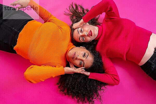 Zwei multiethnische Frauen in trendiger Pose auf rosa Hintergrund  Lifestyle