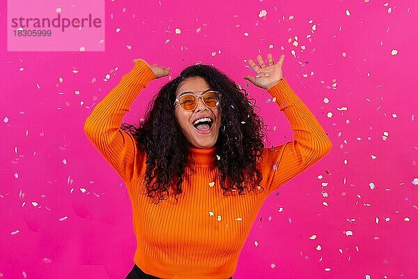 Lächelnd werfen Konfetti  Curly-haired Frau auf einem rosa Hintergrund  Disco-Party-Konzept