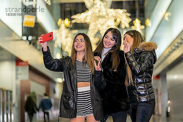 Weihnachten in der Stadt bei Nacht  Dekoration im Winter. Drei Freunde genießen lächelnd ein Selfie machen