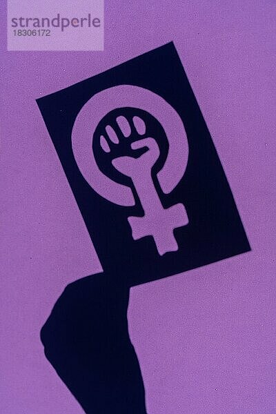 Schatten des Symbols des Kampfes für den Feminismus auf einem lila Hintergrund  geballte Faust einer Frau im Marsch Proteste für die Rechte der Frauen  vertikales Foto