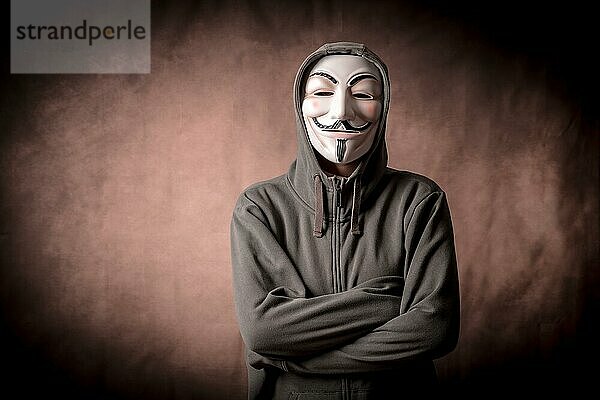 Mann mit anonymer Maske und Sweatshirt  Blick in die Kamera  Studioaufnahme