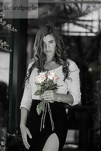 Frau in schwarz-weiß mit farbigen Rosen in der Hand