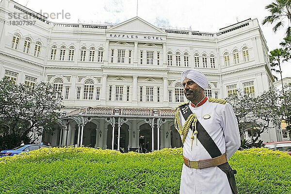 Mann in kolonialer Tracht  hinten das Raffles Hotel  Singapur  Asien