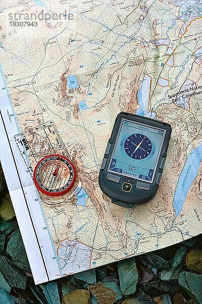 Ein Magnetkompass und ein GPS-Gerät  das die Himmelsrichtungen auf einer Karte anzeigt. Ausgelegt auf einer Schiefertafel
