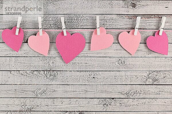 Valentinstag Zusammensetzung mit rosa Papier Herzen hängen von Linie mit Heringen auf hölzernen Hintergrund mit leeren Kopie Raum