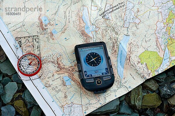 Ein Magnetkompass und ein GPS-Gerät  das die Himmelsrichtungen auf einer Karte anzeigt. Ausgelegt auf einer Schiefertafel