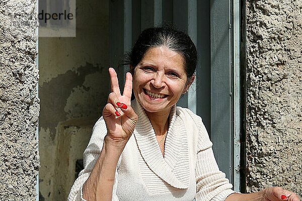 Favela  Frau sitzt am Eingang ihres Hauses und macht eine fröhliche Geste  Belo Horizonte  Minas Gerais  Brasilien  Südamerika