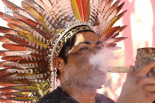 Indigenes Volk  Mann des Urvolkes Fulni-ô trägt traditionellen Kopfschmuck aus Vogelfedern und raucht traditionelle Pfeife  Pernambuco  Brasilien  Südamerika