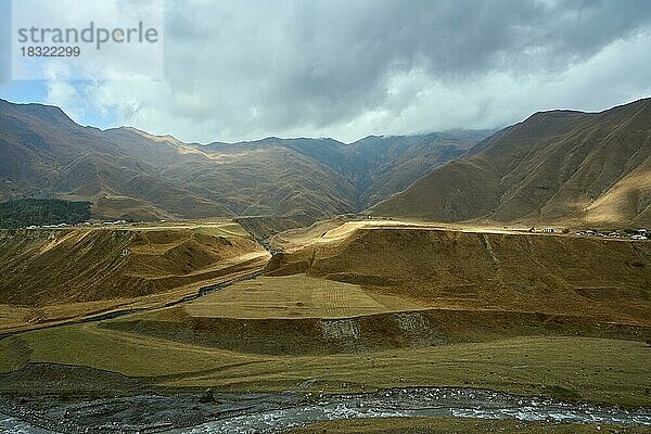 Hochgebirgslandschaft an der georgischen Heerstraße  Flussterrassen  zerschnitten von dem Fluss Kesia  der hier in den Fluss Terek mündet  links der Ort Kanobi  rechts der Ort Goristsikhe  Distrikt Stepantsminda  Region Mtskheta-Mtianeti  Hoher Kaukasus  Georgien  Asien