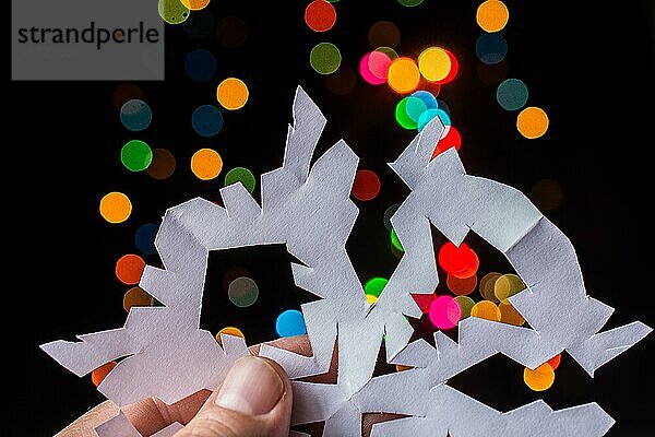 Schneeflocke geformt Papier in der Hand auf Bokeh Licht Hintergrund