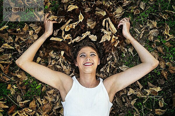 Eine glückliche junge Frau liegt im Herbstlaub. Schöne Augen  warme Gefühle