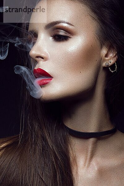 Schöne sexy brunette Mädchen mit hellen Make-up  rote Lippen  Rauchen mit Rauch aus dem Mund. Schönheit Gesicht. Fotos im Studio auf einem schwarzen Hintergrund geschossen