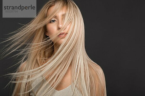 Schönes blondes Mädchen in Bewegung mit einem perfekt glatten Haar  und klassisches Make-up. Schönes Gesicht. Bild im Studio aufgenommen