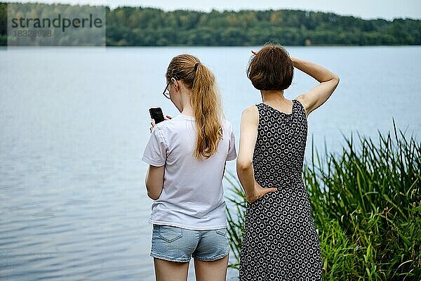 Mutter und Tochter sind an das Ufer des Sees gekommen und erkunden die Umgebung