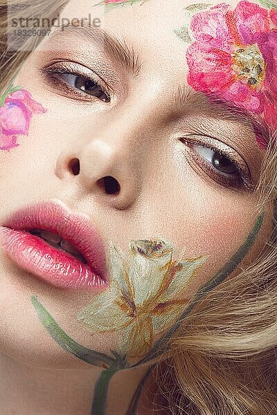 Schönes blondes Mädchen mit Locken und einem Blumenmuster auf dem Gesicht. Schönheit Blumen. Porträtaufnahme im Studio