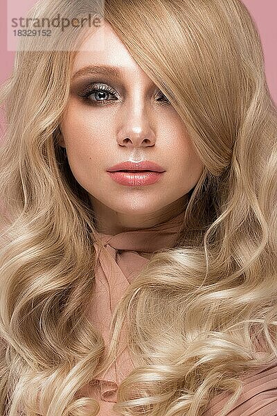 Schöne blonde Mädchen mit Locken Haar  sieht aus wie eine Puppe  mit glamourösen Make-up in rosa Kleidung. Schönes Gesicht. Foto im Studio aufgenommen