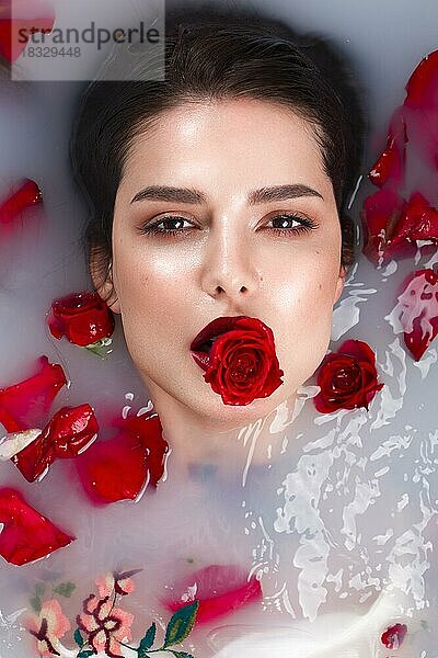 Schönes Mädchen mit klassischem Make-up und roten Lippen im Badezimmer mit Blumen. Schönes Gesicht. Foto im Studio aufgenommen