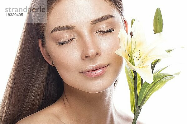 Schönes junges Mädchen mit einem leichten natürlichen Make-up und perfekter Haut mit Blumen in der Hand. Schönes Gesicht. Bild im Studio auf einem weißen Hintergrund aufgenommen