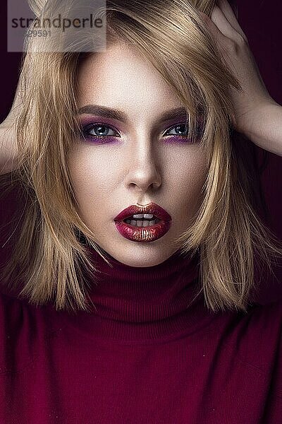 Schöne blonde Frau in einem roten Pullover mit hellem Make-up und dunklen Lippen. Schönes Gesicht. Bild im Studio aufgenommen