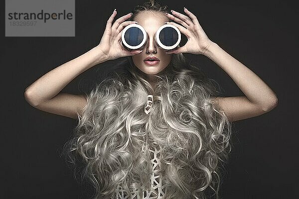 Schönes Mädchen in Kunst Kleid und Avantgarde-Frisuren mit kosmetischen Produkten in ihren Händen. Schönes Gesicht. Fotos im Studio aufgenommen