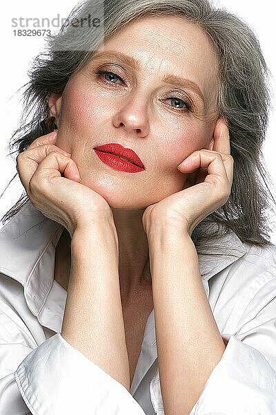 Porträt einer schönen älteren Frau im weißen Hemd mit klassischem Make-up und grauem Haar