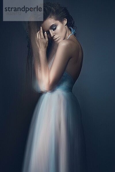 Schönes Mädchen in einem hellblauen Kleid und lange Haare in einem modischen Bild. Schönheit Mode-Stil. Bild im Studio mit gemischtem Licht aufgenommen